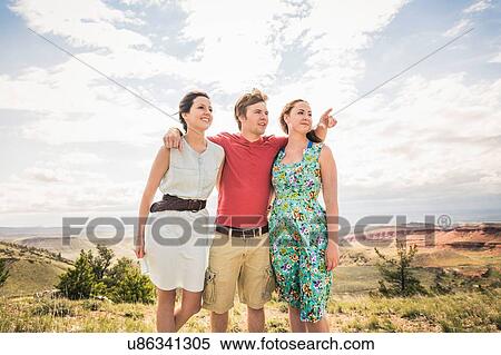 Stock Photography - Young man with arm around two young women in hills, Bridger, Montana, USA. Fotosearch