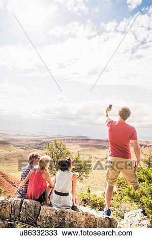 Stock Image - Young man with friends taking smartphone selfie in landscape, Bridger, Montana, USA. Fotosearch
