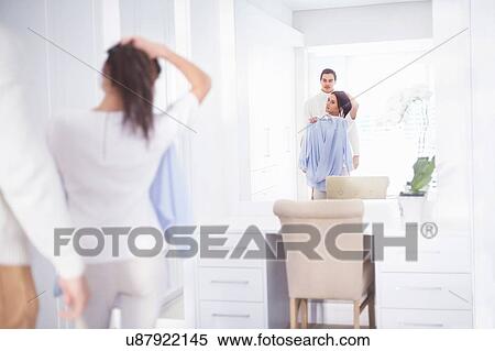 Stock Photography - Young woman and boyfriend getting ready in bedroom mirror. Fotosearch