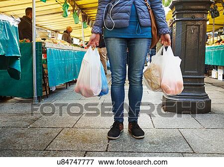 "Young woman at market, holding bags of shopping, low section" View Large Photo Image Stock Photo - "Young woman at market, holding bags of shopping, low section". Fotosearch