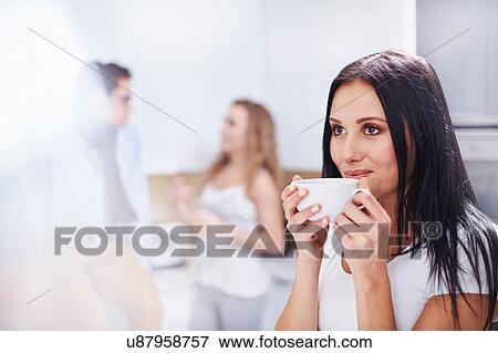 Stock Photo - Young woman drinking coffee in kitchen. Fotosearch
