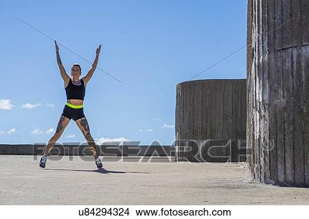 Picture - Young woman exercising outdoors. Fotosearch