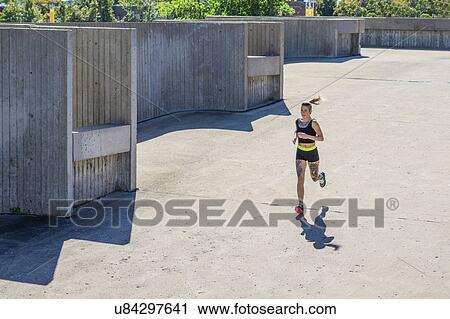 Stock Image - "Young woman exercising, running, outdoors". Fotosearch