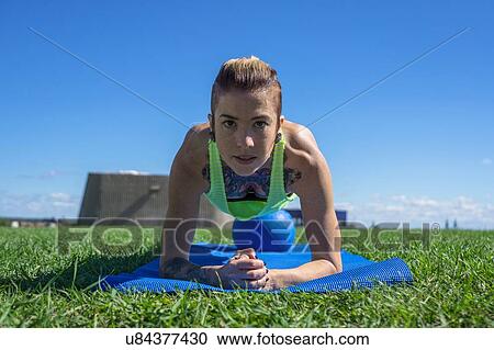 Stock Image - "Young woman exercising with ball, outdoors". Fotosearch