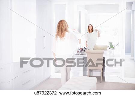 Stock Image - Young woman getting ready in bedroom mirror. Fotosearch