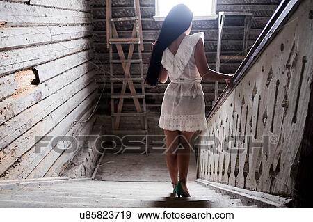 Young woman going down staircase View Large Photo Image Stock Photo - Young woman going down staircase. Fotosearch