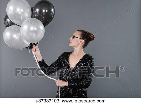 Young woman holding black and white balloons, grey background View Large Photo Image Stock Image - Young woman holding black and white balloons, grey background. Fotosearch