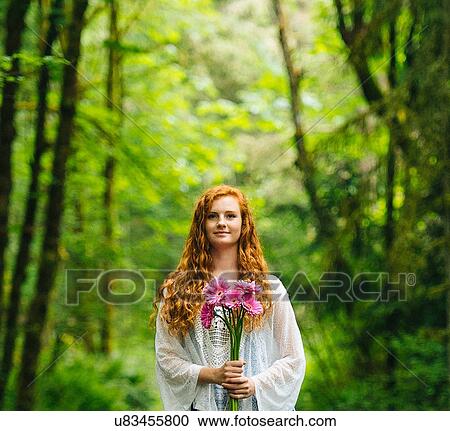Young woman holding bunch of pink gerberas in forest View Large Photo Image Stock Image - Young woman holding bunch of pink gerberas in forest. Fotosearch