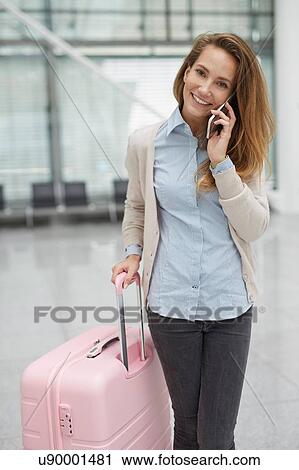 Young woman holding pink suitcase using smartphone looking at camera smiling View Large Photo Image Stock Image - Young woman holding pink suitcase using smartphone looking at camera smiling. Fotosearch