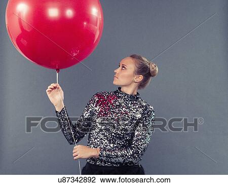 Young woman holding red balloon, grey background View Large Photo Image Stock Image - Young woman holding red balloon, grey background. Fotosearch
