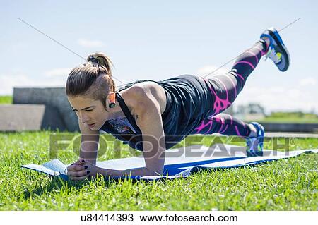 Stock Image - "Young woman holding yoga position, outdoors". Fotosearch