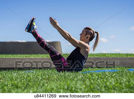 Stock Photo - "Young woman holding yoga position, outdoors". Fotosearch