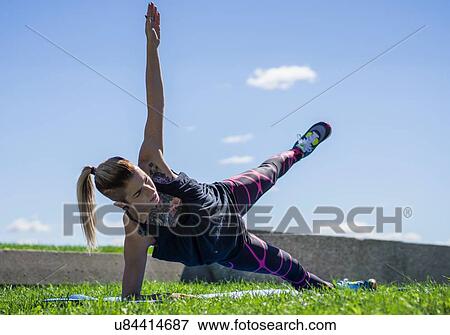 Stock Photo - "Young woman holding yoga position, outdoors". Fotosearch