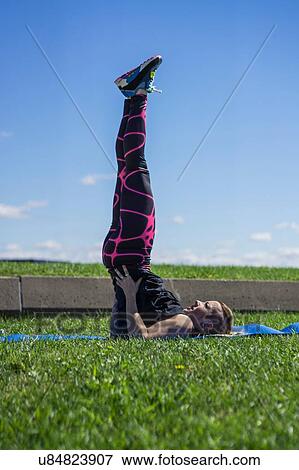 Stock Photo - "Young woman holding yoga position, outdoors". Fotosearch