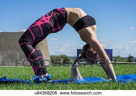 Stock Photograph - "Young woman holding yoga position, outdoors". Fotosearch