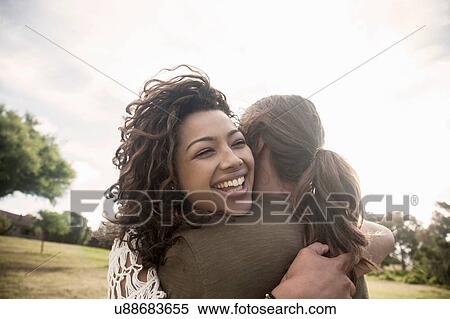 Stock Photography - Young woman hugging young man eyes closed smiling. Fotosearch