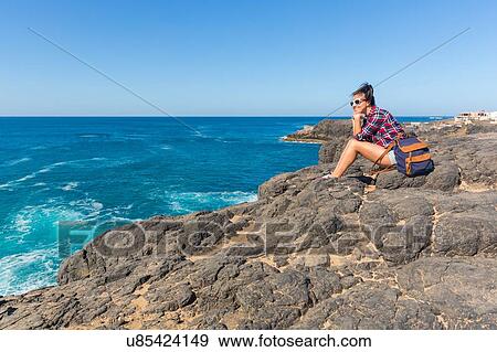 Young woman looking out to sea from rocks, El Cotillo, Fuerteventura, Spain View Large Photo Image Stock Photo - Young woman looking out to sea from rocks, El Cotillo, Fuerteventura, Spain. Fotosearch
