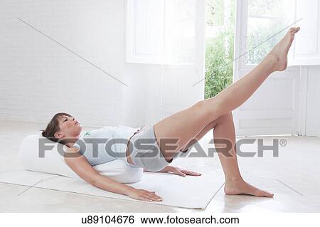 Young woman lying on back exercising at home View Large Photo Image Stock Photograph - Young woman lying on back exercising at home. Fotosearch