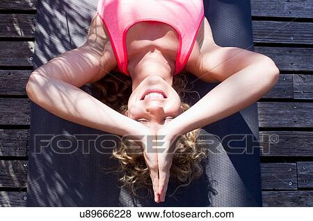 Stock Photo - Young woman lying on back in prayer pose, high angle. Fotosearch