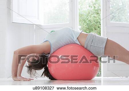Young woman lying on back on pink exercise ball at home View Large Photo Image Stock Photo - Young woman lying on back on pink exercise ball at home. Fotosearch