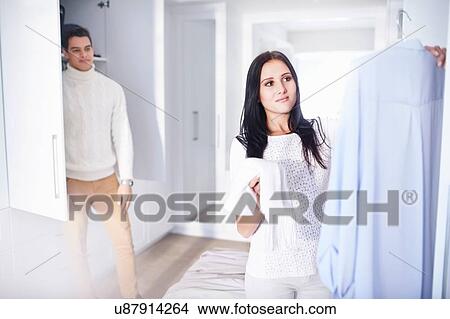 Picture - Young woman making decisions whilst getting ready in bedroom. Fotosearch
