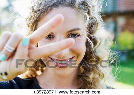 Stock Image - Young woman making peace sign with hand. Fotosearch
