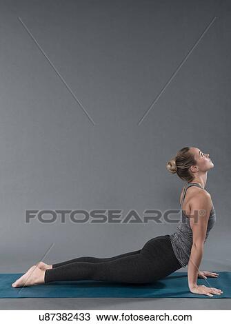 Stock Image - Young woman practising yoga, grey background. Fotosearch