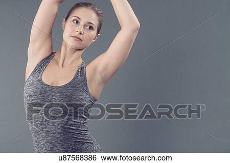 Stock Photograph - Young woman practising yoga, grey background. Fotosearch