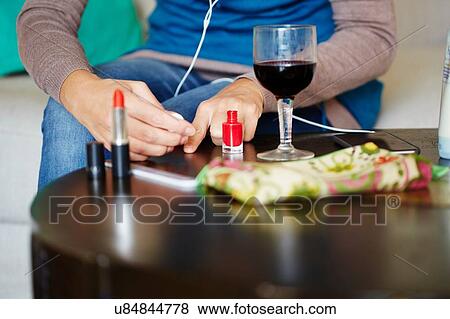 "Young woman sitting at table applying nail varnish, mid section" View Large Photo Image Stock Photo - "Young woman sitting at table applying nail varnish, mid section". Fotosearch