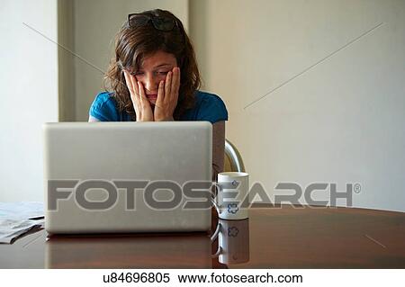 "Young woman sitting at table using laptop, looking stressed" View Large Photo Image Stock Photography - "Young woman sitting at table using laptop, looking stressed". Fotosearch