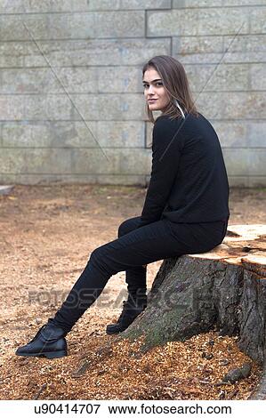 Young woman sitting on tree stump View Large Photo Image Stock Photo - Young woman sitting on tree stump. Fotosearch