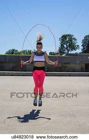 Stock Photo - "Young woman skipping with rope, outdoors". Fotosearch