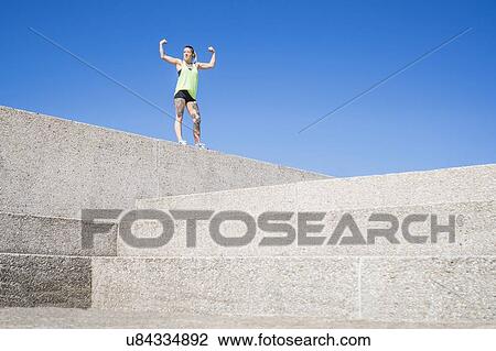 "Young woman standing on concrete ledge, flexing muscles" View Large Photo Image Stock Image - "Young woman standing on concrete ledge, flexing muscles". Fotosearch
