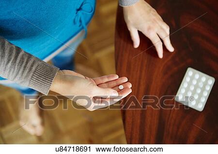 Stock Image - "Young woman taking medication from blister pack, close-up". Fotosearch