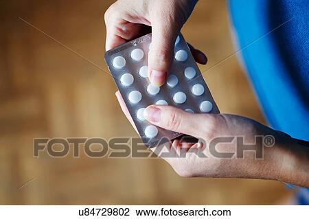 Stock Image - "Young woman taking medication from blister pack, close-up". Fotosearch