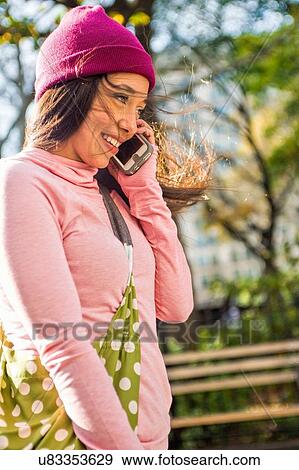 Stock Photo - Young woman using smartphone in park. Fotosearch