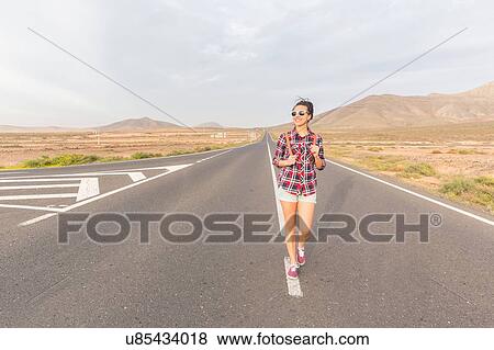 Stock Photo - Young woman walking along road, La Oliva, Fuerteventura, Spain. Fotosearch
