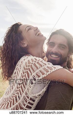 Young woman with arms around young man, throwing head back laughing View Large Photo Image Stock Image - Young woman with arms around young man, throwing head back laughing. Fotosearch