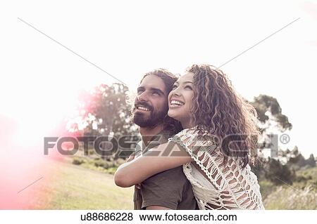 Young woman with arms around young man looking up smiling View Large Photo Image Stock Photo - Young woman with arms around young man looking up smiling. Fotosearch