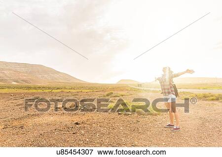 Young woman with arms open in sunlit volcanic landscape, La Oliva, Fuerteventura, Spain View Large Photo Image Stock Photo - Young woman with arms open in sunlit volcanic landscape, La Oliva, Fuerteventura, Spain. Fotosearch