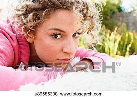 Stock Photo - Young woman with hands on chin looking at camera. Fotosearch