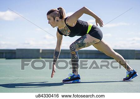 Stock Photograph - "Young woman with tattoos, preparing for race". Fotosearch