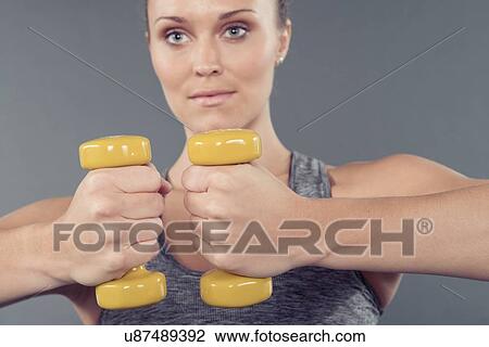 Young woman working out with dumbbells, grey background View Large Photo Image Stock Image - Young woman working out with dumbbells, grey background. Fotosearch