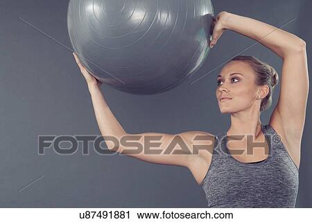 Young woman working out with gym ball, grey background View Large Photo Image Stock Image - Young woman working out with gym ball, grey background. Fotosearch
