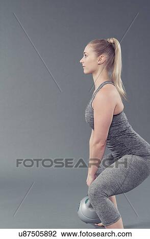 Young woman working out with kettlebell, grey background View Large Photo Image Stock Image - Young woman working out with kettlebell, grey background. Fotosearch
