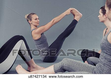 Picture - Young women doing stretching exercise, grey background. Fotosearch