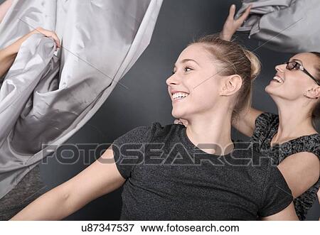 Young women holding cloth over head, grey background View Large Photo Image Stock Photo - Young women holding cloth over head, grey background. Fotosearch