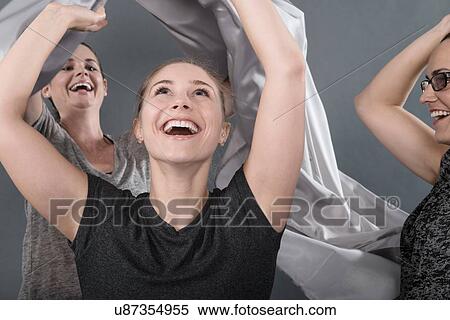 Young women holding cloth over head, grey background View Large Photo Image Stock Photography - Young women holding cloth over head, grey background. Fotosearch