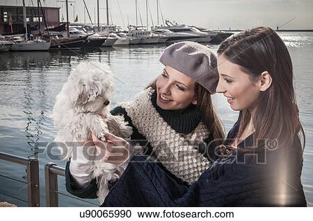 Young women in boatyard holding up dog smiling View Large Photo Image Stock Image - Young women in boatyard holding up dog smiling. Fotosearch