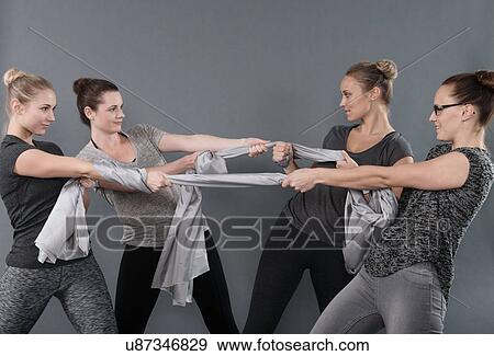 Young women playing tug of war, grey background View Large Photo Image Stock Photo - Young women playing tug of war, grey background. Fotosearch